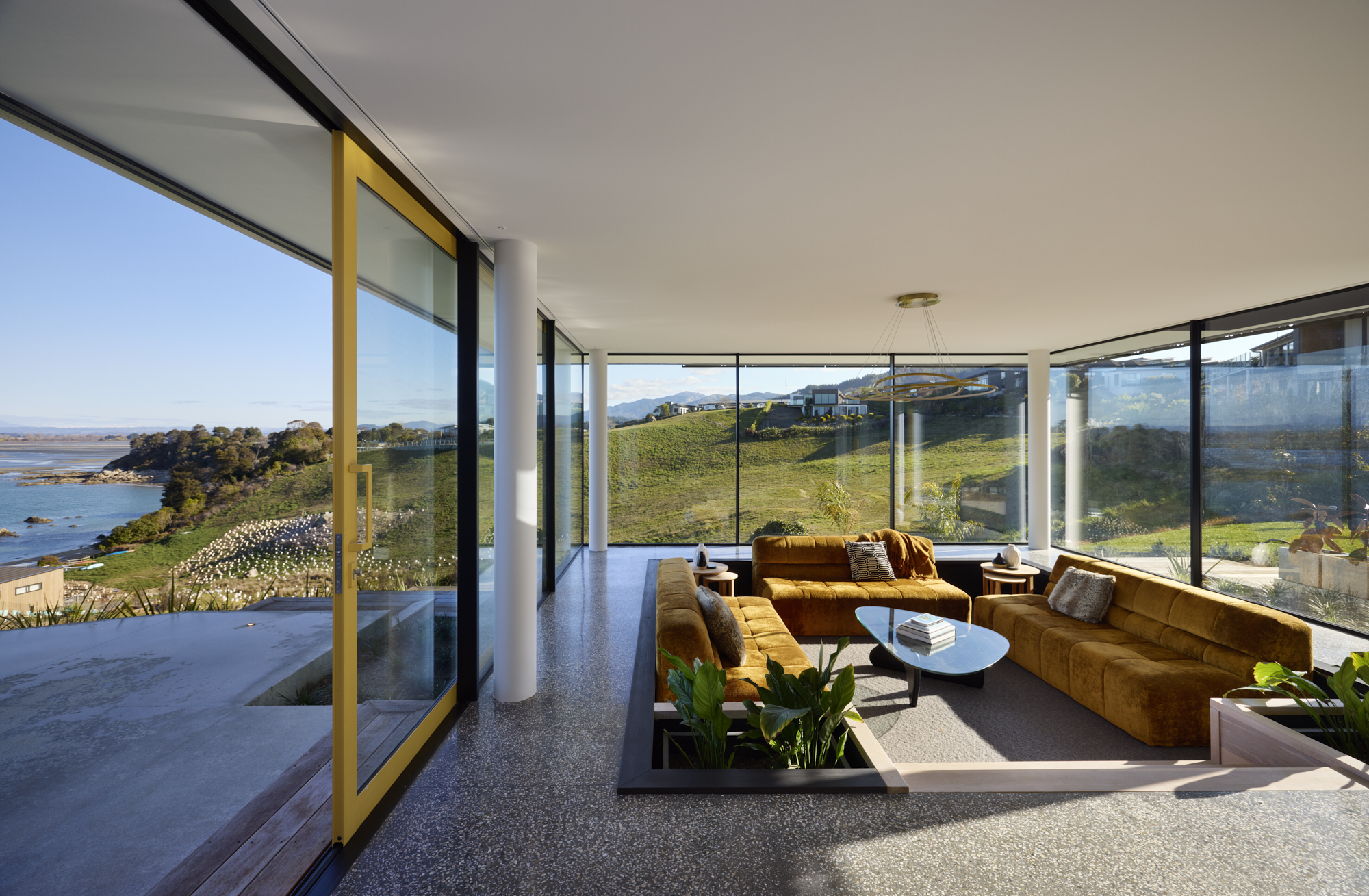 A sunken lounge room overlooking the coastline featuring large FMI Building Innovation Ultra Clear (low iron) glass windows and sliding doors